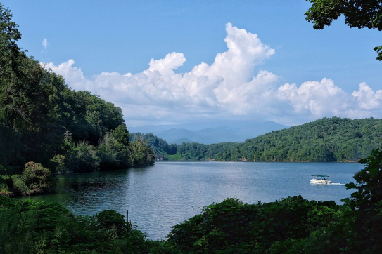 Calm lake with mountains in the background and one pleasure boat.